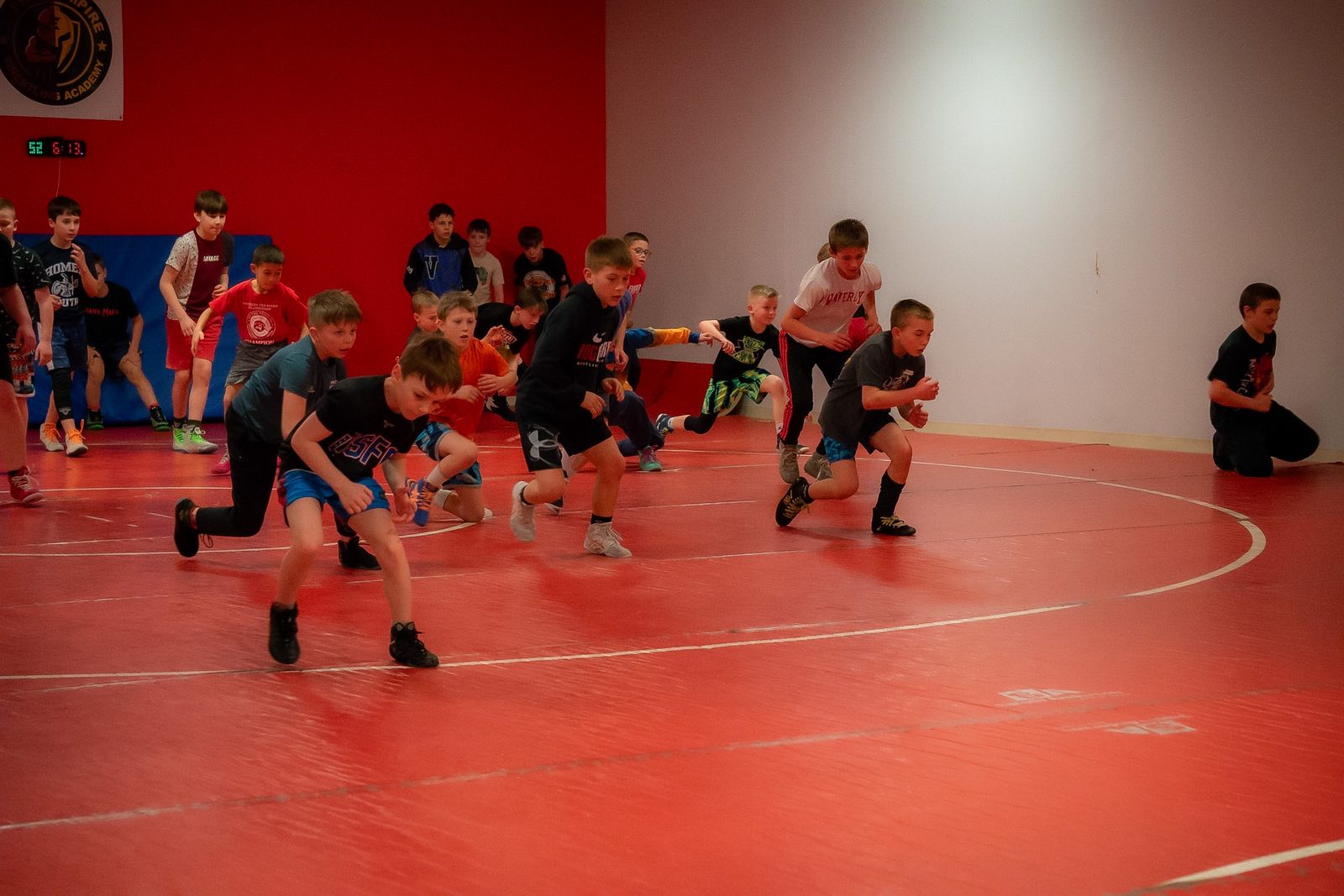 Young wrestlers sprinting across the mat at Frog Empire Wrestling Academy